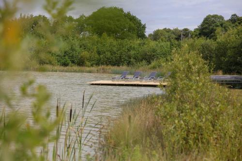 a group of chairs sitting on a dock on a lake at Hastings Retreat Rural barn conversions with Private Lake in Ashby de la Zouch