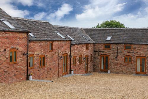 a brick building with a bunch of windows at Hastings Retreat Rural barn conversions with Private Lake in Ashby de la Zouch