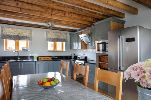 a kitchen with a table with a bowl of fruit on it at Hastings Retreat Rural barn conversions with Private Lake in Ashby de la Zouch