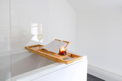 a tray with a book and a candle and a wine glass at Hastings Retreat Rural barn conversions with Private Lake in Ashby de la Zouch
