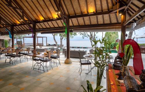 a restaurant with tables and chairs and a view of the ocean at Mimpi Resort Tulamben in Tulamben