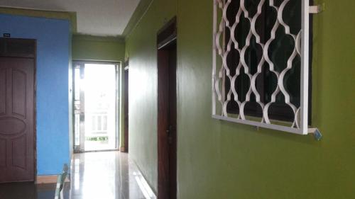 a hallway with green walls and a door with a window at Leosim Hotel Nebbi in Nebbi