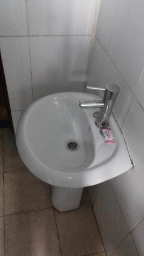 a white bidet in a bathroom with a tile wall at Leosim Hotel Nebbi in Nebbi