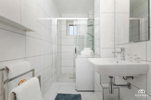 uma casa de banho branca com um lavatório e um chuveiro em Apartament Gryf Szczecin em Szczecin