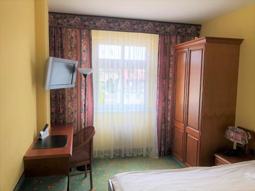 a bedroom with a bed and a desk and a television at Brandiser Parkhotel in Brandis