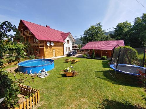 a backyard with a house and a yard with two swings at Садиба Чорногора in Yaremche