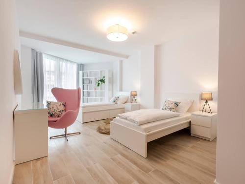 a white living room with a bed and a chair at VacationClub – Seaside Park Penthouse 608 in Kołobrzeg