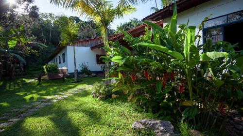 a garden with a house and a bench in the background at Pousada Salve Floresta in Tapiraí