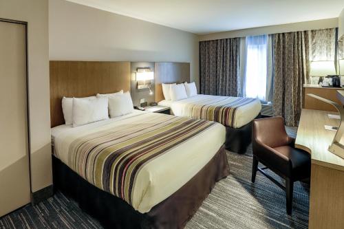 a hotel room with two beds and a chair at Country Inn & Suites by Radisson Nashville Airport TN in Nashville