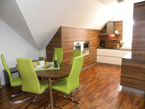 a kitchen and dining room with a wooden table and green chairs at Apartment WELLNESS Vlčková in Vlčková