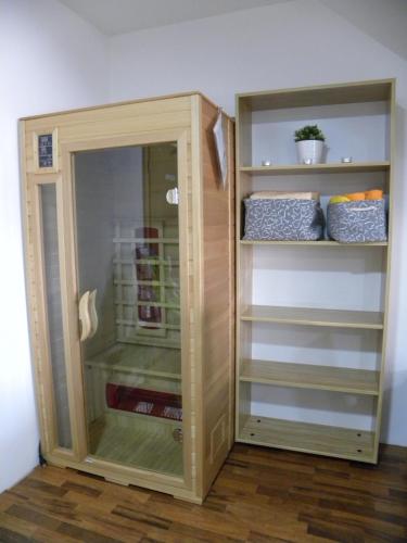 a wooden closet with a glass door and shelves at Apartment WELLNESS Vlčková in Vlčková