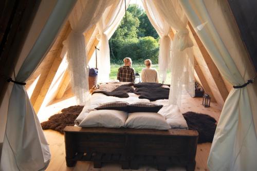 dos personas sentadas en una cama en una tienda en Sandfallet Glamping en Laholm