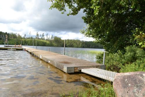 a dock on a lake with people sitting on it at Lust Huset in Ambjörnarp