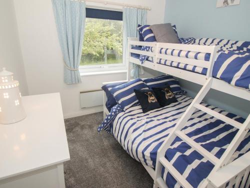 a bedroom with two bunk beds and a window at Galwad Y Môr in Pwllheli