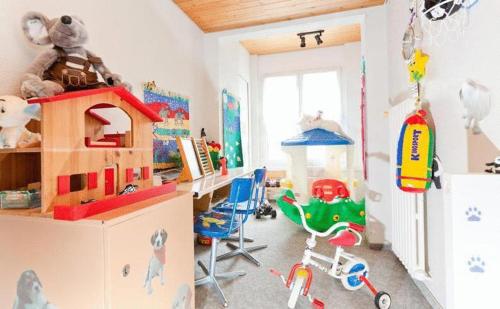 Hotel Piz Badus في أندرمات: غرفة أطفال بها ألعاب ومكتب ومنطقة لعب