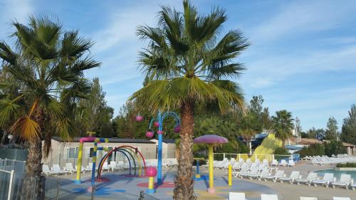 um parque infantil com uma palmeira numa piscina em Mobil home La Mer em Vias