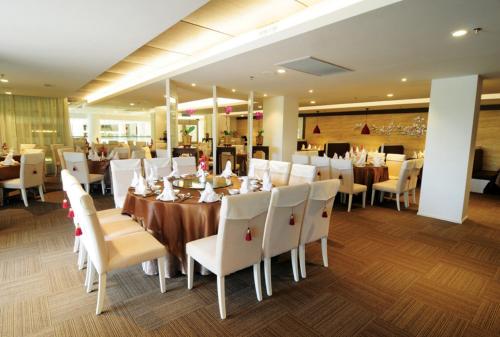 a dining room with tables and white chairs at Kings Green Hotel City Centre Melaka in Melaka
