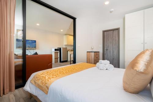 - une chambre avec un grand lit blanc et un grand miroir dans l'établissement The Apartment at The Title Residencies Naiyang Beach, à Phuket
