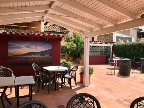 a patio with tables and chairs under a pergola at Hostal Can Pou in Vidreres