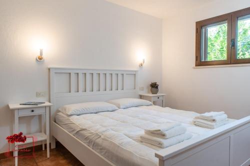 Un dormitorio blanco con una cama grande con toallas. en Casa Corallo, en Baratili San Pietro