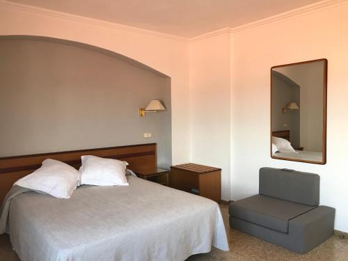 a bedroom with a bed and a mirror and a chair at Hostal Can Pou in Vidreres