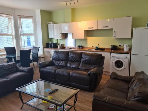 a living room with a couch and a table and a kitchen at Yarmouth Apartments, Street Permit Parking, Close To Everything, Beach, Pier, Free WIFI in Great Yarmouth