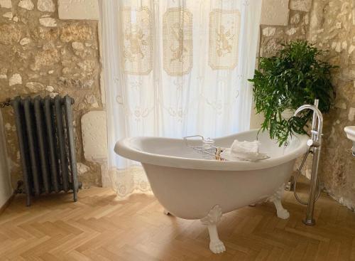 a white bath tub sitting in a bathroom next to a window at La Maison in Siracusa