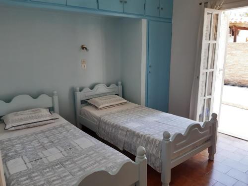 2 camas en un dormitorio con paredes azules y ventana en Villa Evdokia, en Katakolon