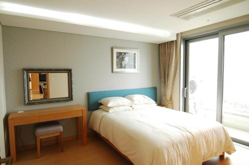 1 dormitorio con cama, mesa y espejo en Keumho Jeju Resort, en Seogwipo