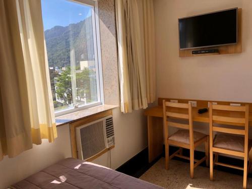 1 dormitorio con cama, ventana y escritorio en Tropical Barra Hotel, en Río de Janeiro