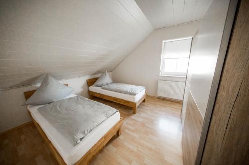 a attic bedroom with two beds and a window at Ferienwohnung Nallenblick in Gersfeld