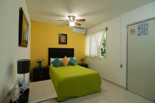 - une chambre avec un lit vert et un ventilateur de plafond dans l'établissement El Rincon de Los Angeles, à Colima