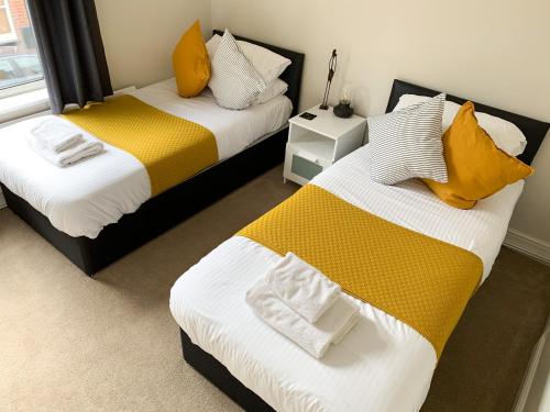 two beds in a room with yellow and white at The Racecourse - Quaint Victorian Home With Free Parking in York