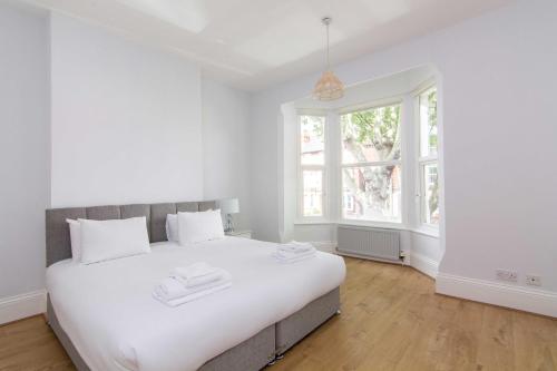 ein weißes Schlafzimmer mit einem großen Bett und Fenstern in der Unterkunft Spacious 4 bed with Parking near Nottingham City Centre - 184 Gregory House in Nottingham