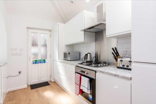 a kitchen with white cabinets and a stove top oven at Spacious 4 bed with Parking near Nottingham City Centre - 184 Gregory House in Nottingham