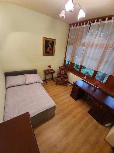 a bedroom with a bed and a desk and windows at Willa Widok in Nałęczów