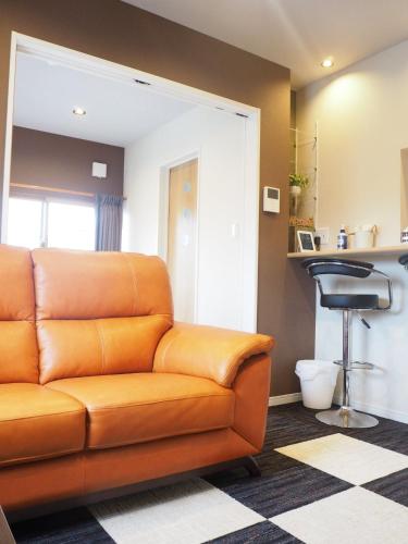 an orange couch in a living room with a bar stool at Harbour Inn & Suites - Vacation STAY 8829 in Niigata