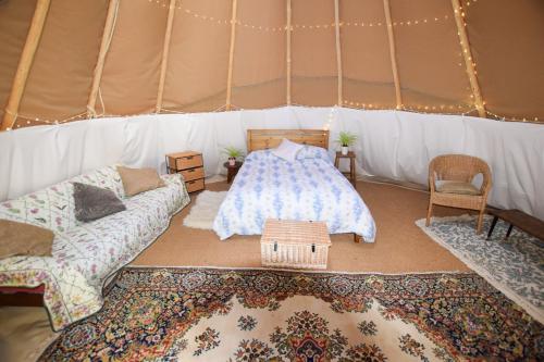 a room with a tent with a bed and a rug at Dragonfly Lodge Ifold & Alpaca My Tipi Glamping in Billingshurst