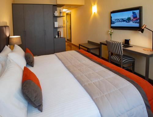a large bed in a hotel room with a television at Hotel Grand Brizo Buenos Aires in Buenos Aires