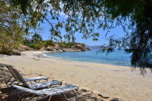 a beach with two lounge chairs and the ocean at Beach house set in a beautiful bay in Aëtós