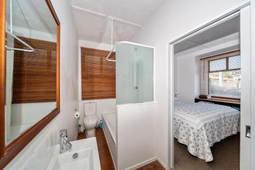 a bathroom with a bed and a sink and a mirror at Richard & Jill's City House in New Plymouth