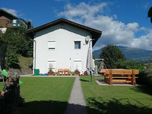 una casa bianca con panchina e ombrellone di Ferienwohnung Kerschbaumer a Seeboden