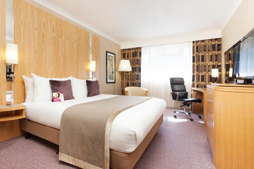 um quarto de hotel com uma cama e uma televisão de ecrã plano em Crowne Plaza Reading em Reading