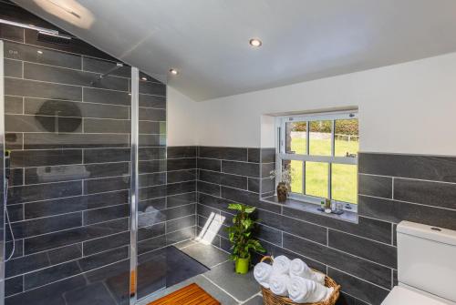 a bathroom with a shower with black tiles at Whicham Hall in Silecroft