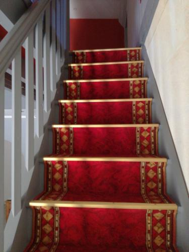 a set of stairs with red carpet and gold rails at Le Moulin du Galant in Ménesplet