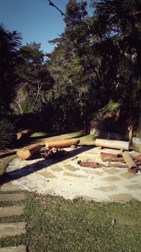una pila de troncos y un banco en un parque en Casa no Céu, en Petrópolis