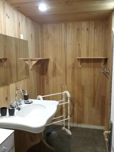 La salle de bains est pourvue d'un lavabo blanc et de murs en bois. dans l'établissement La Tireliere, longère bord de mer avec jardin, à Surville