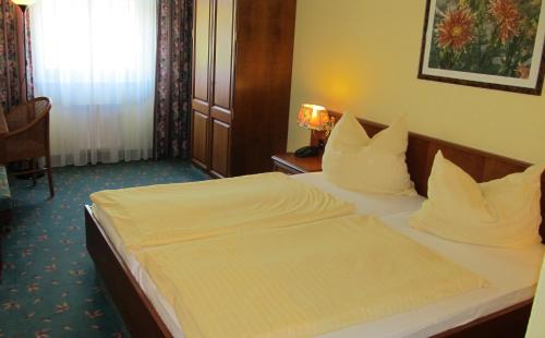 a bedroom with a bed with white sheets and pillows at Brandiser Parkhotel in Brandis