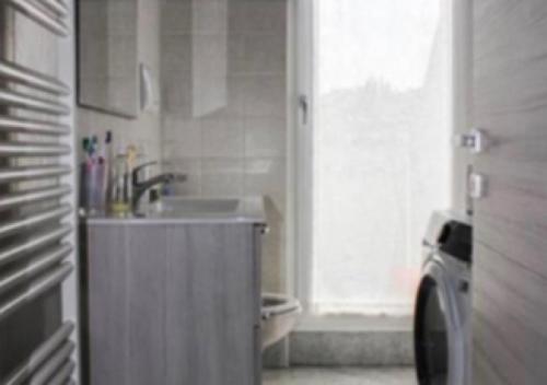 uma pequena cozinha com um lavatório e uma janela em La Magnolia Apartments II em Desenzano del Garda