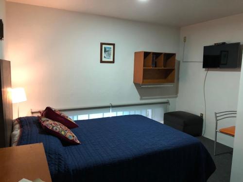 a bedroom with a blue bed and a television at Hostel Lit Guadalajara in Guadalajara